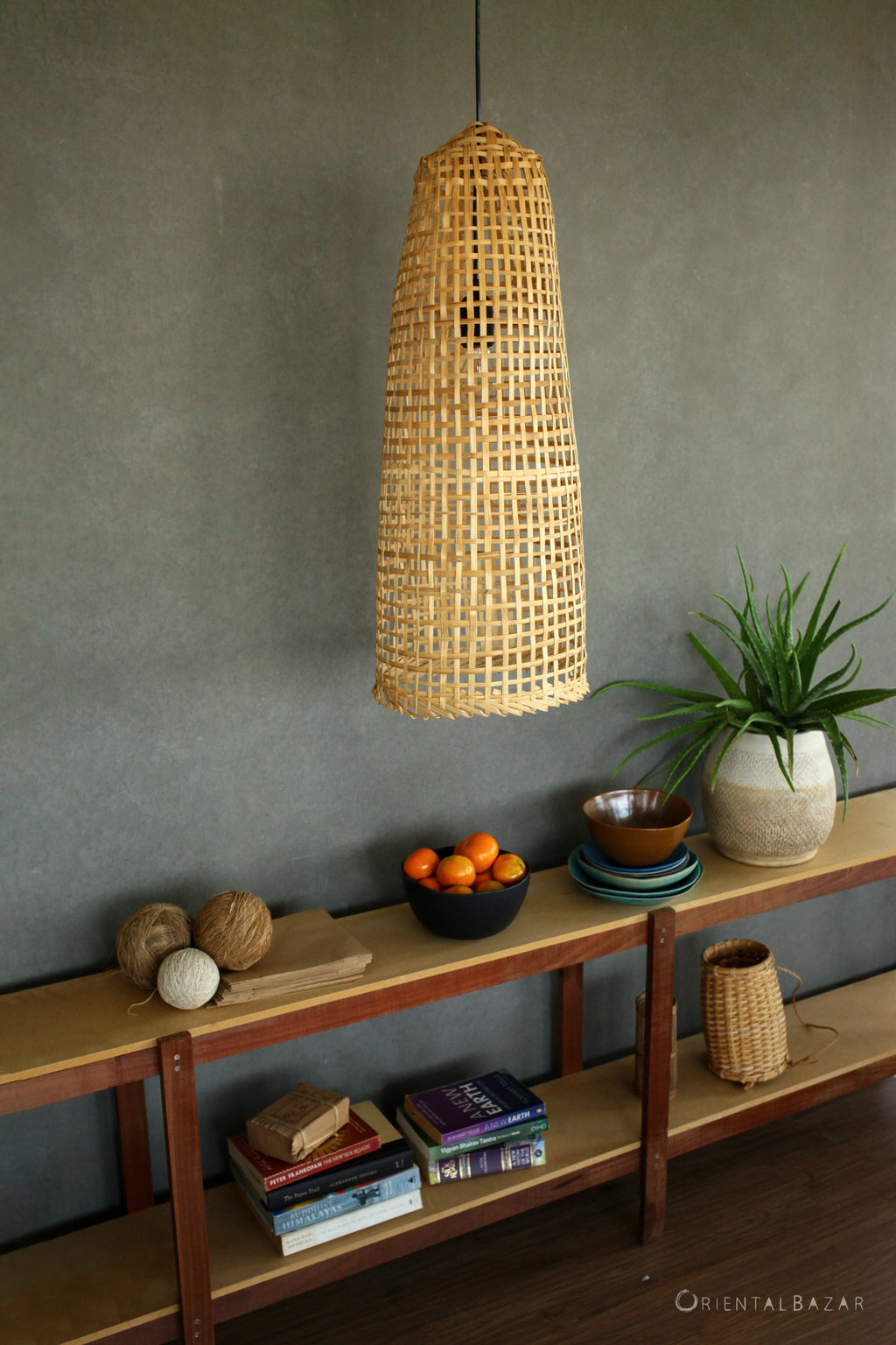 Rustic Bamboo pendant light hanging above a wooden shelf with books and decorative items.