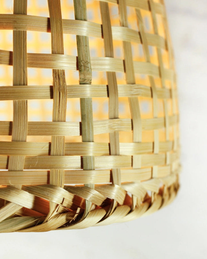 Closeup of a rustic woven bamboo lampshade on a white background