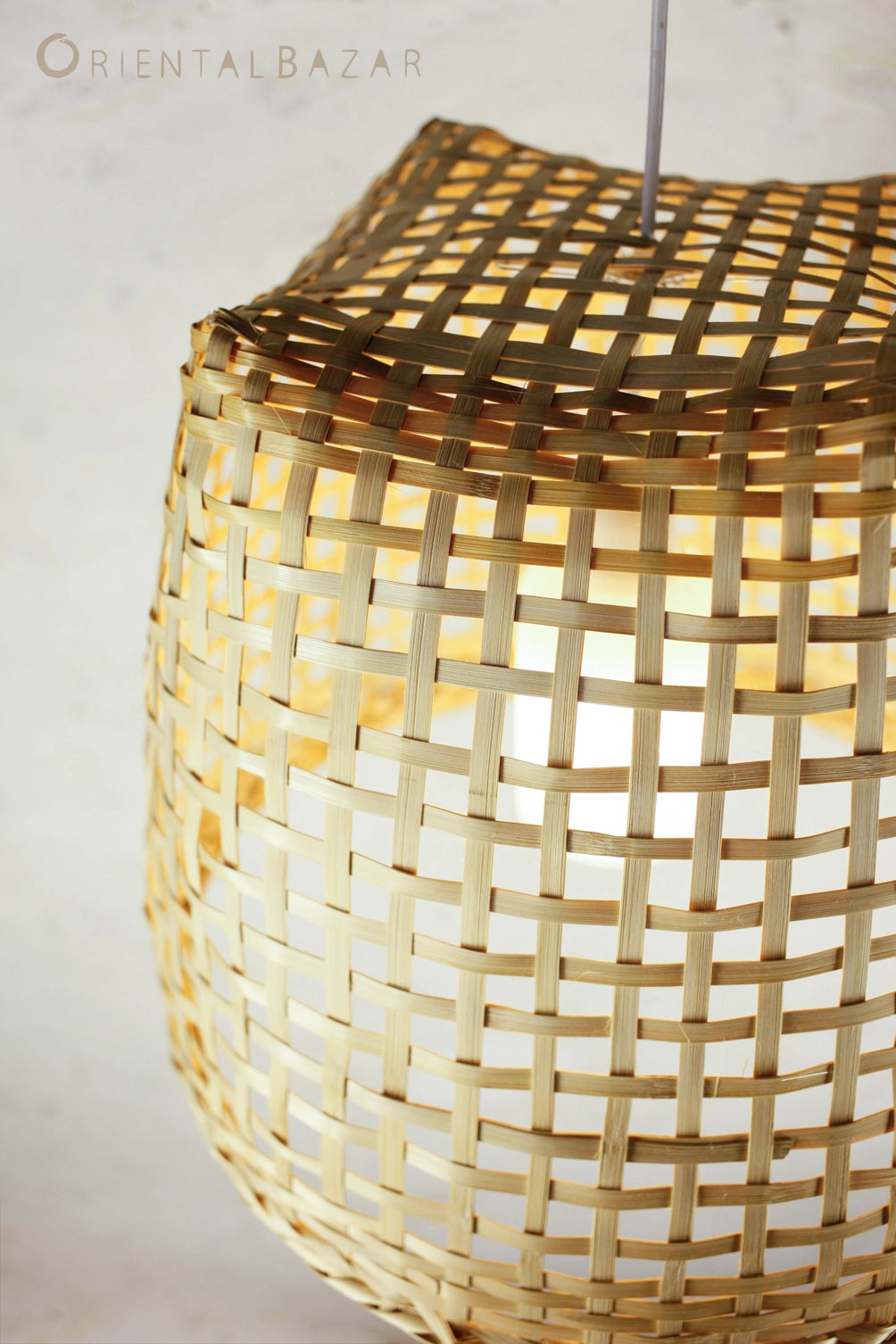 Rustic handwoven bamboo lamp with a warm glow on a plain background