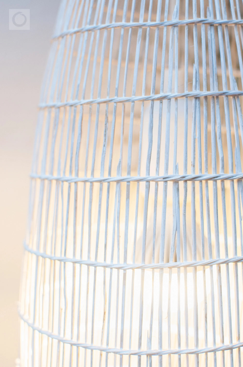 Close-up of a white woven bamboo light fixture with a neutral background