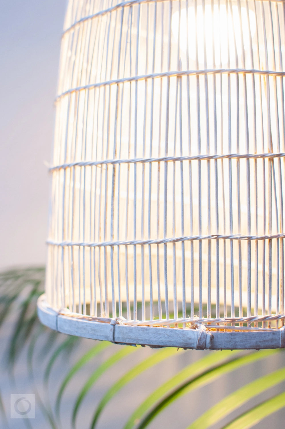 Close-up of a white wicker bamboo lampshade with a blurred natural background