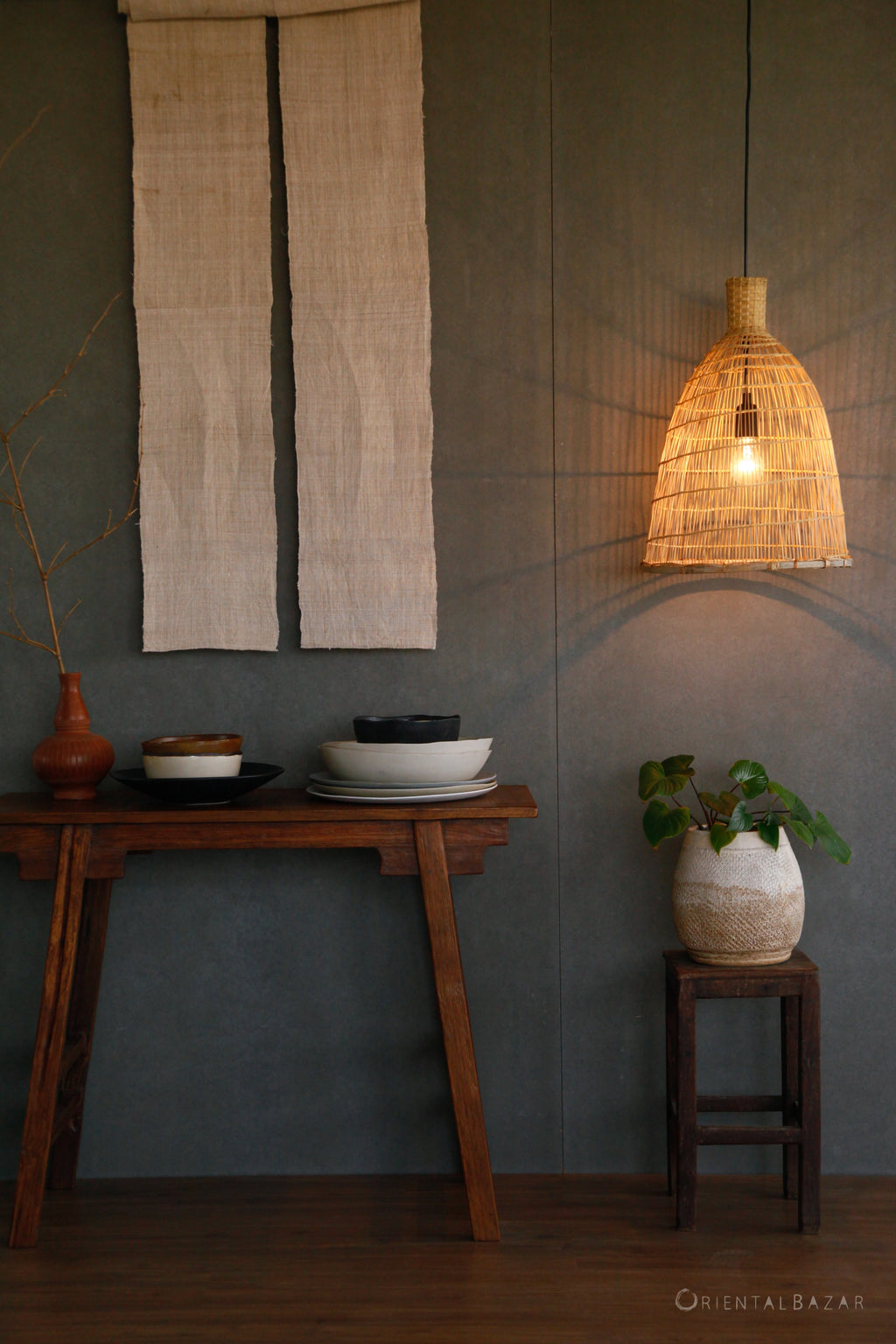 Nestled interior with wooden table, bamboo hanging lamp, and wall art