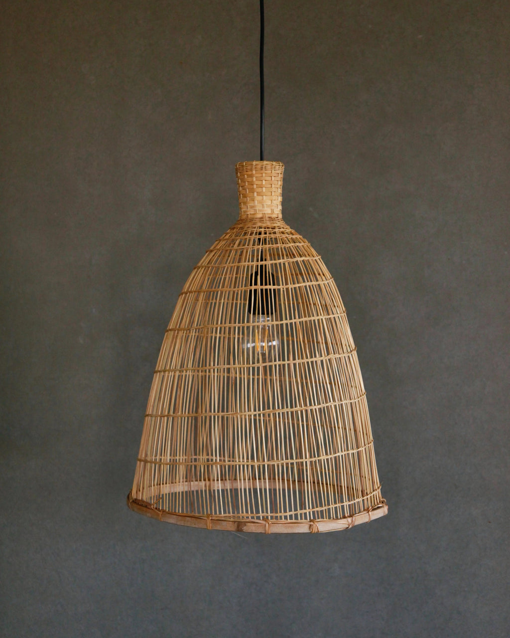 Woven bamboo and rattan pendant light against a dark gray background